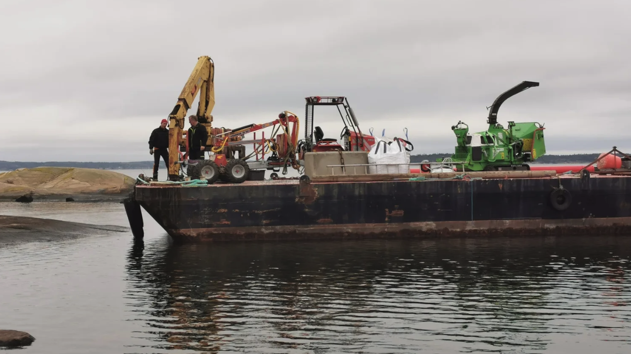 Tungt utstyr på lekter for trefelling langs kyst